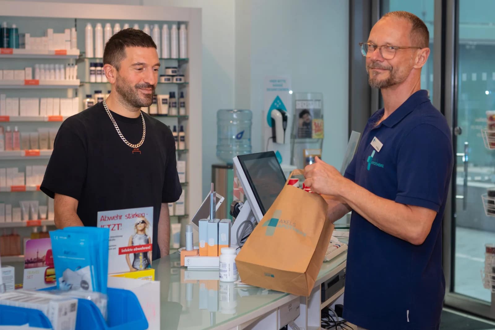 Matthias Philipp übergibt einem Kunden eine Apothekentüte