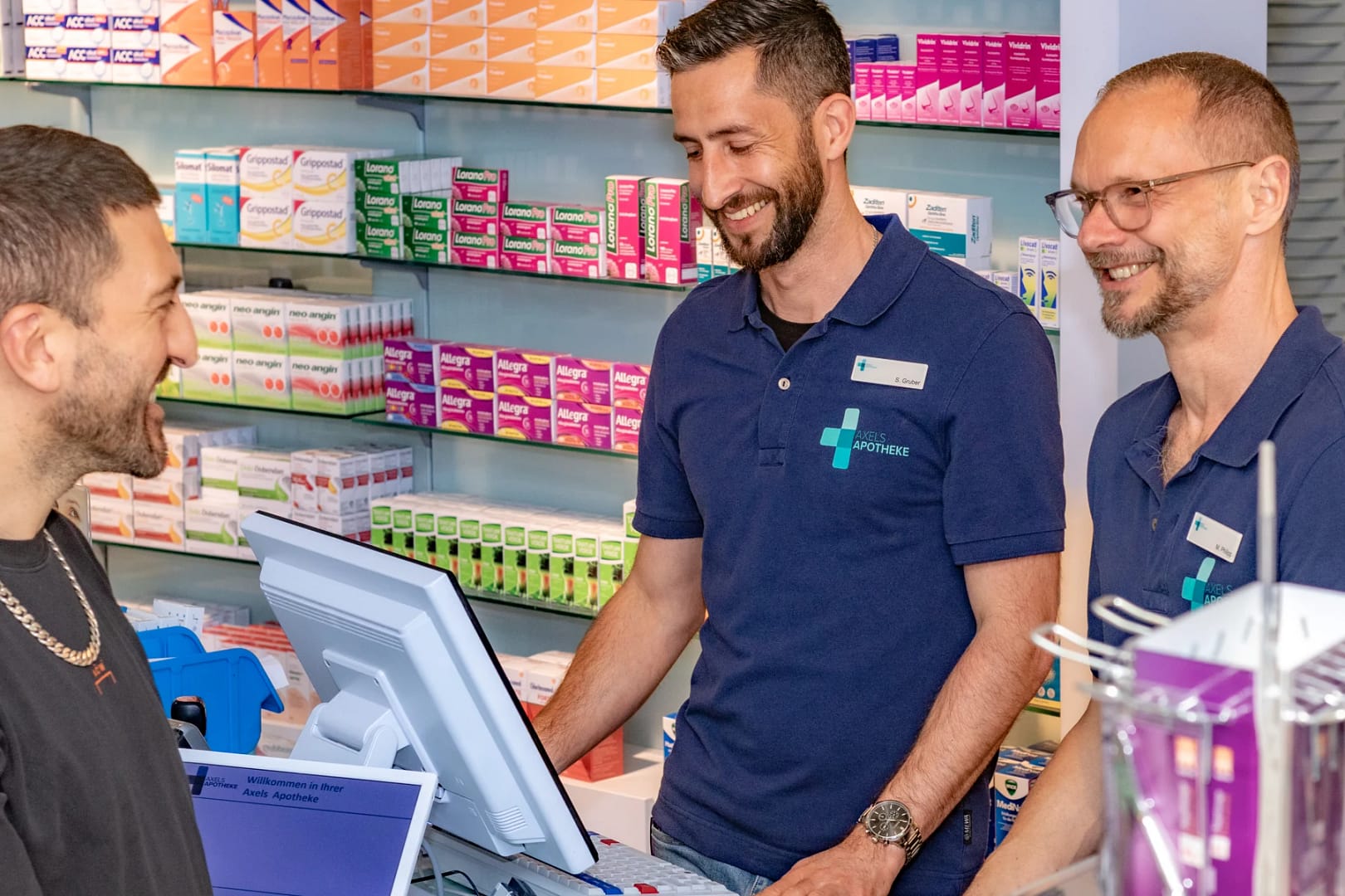 Ein Kunde im Gespräch mit zwei Mitarbeitern in Axels Apotheke