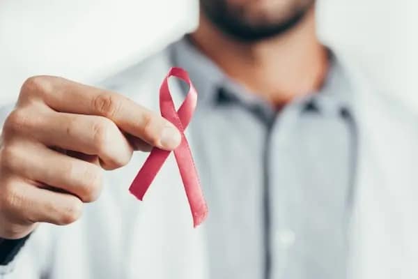 Eine Person hält eine rote HIV-Schleife