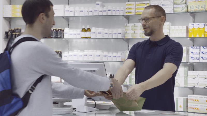 Matthias Philipp übergibt einem Kunden eine Apothekentüte